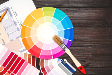 Color palettes with building plan and paint brush on wooden background
