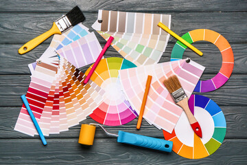 Color palettes with roller and paint brushes on wooden background