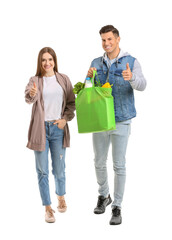 Couple with food in bag showing thumb-up gesture on white background
