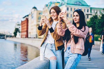 Fascinated hipster tourists dressed in casual apparel strolling on street of new city while shoot...