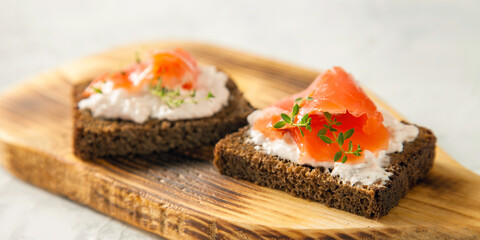 cheese, red fish and arugula sandwich on a board, selective focus, copy space