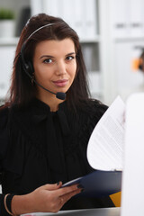 Three call centre service operators at work. Portrait of smiling pretty brunette woman at workplace...