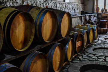 Vintage old oak barrels of wine, cognac in the wine dark vaults of the winery. Selective soft focus. Shooting in the dark