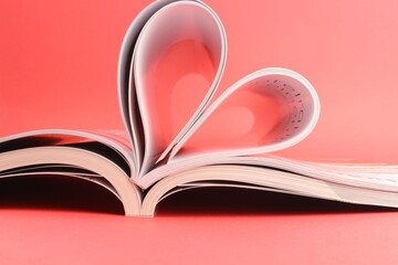 Magazine zu einem Herz geformt mit rotem Hintergrund steht für die Liebe zum Lesen und romanitische Schriften