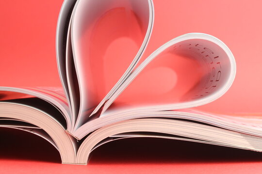 Magazine zu einem Herz geformt mit rotem Hintergrund steht für die Liebe zum Lesen und romanitische Schriften