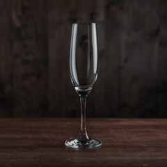Empty champagne glass on wooden table against dark background in bar. Catering Concept