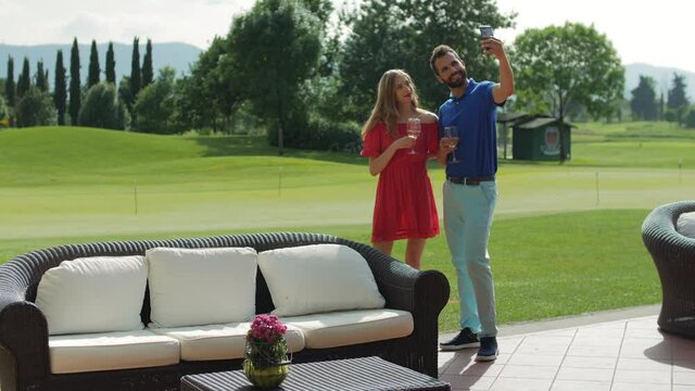 WS Couple enjoying white wine and taking selfie at golf course / Prato, Florence, Italy