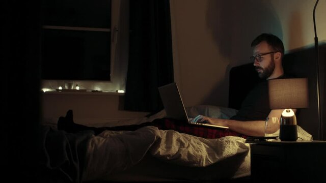 MS Man using laptop in bed at night / UK