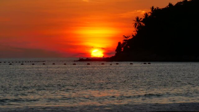 moving water wave hit sand shore coast, nobody on beach, sunset behind tree mountain cape, colorful orange twilight sky background at evening time