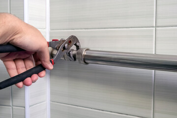 Close up of hand repairing pipes with wrench. Plumber fixing pipe with adjustable wrench.