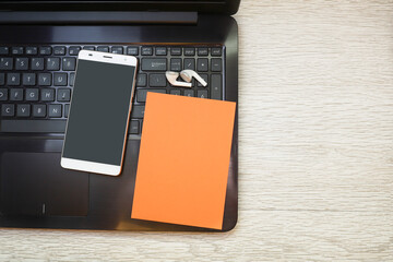 A smartphone and a piece of paper on a computer keyboard on wooden table 