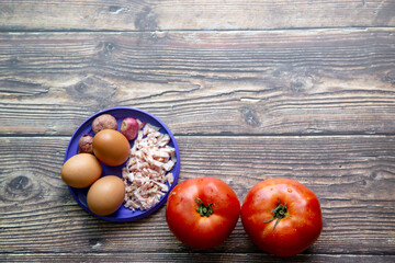 Fresh tamatos and eggs in cooking set.