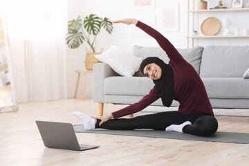 Arabic Woman Doing Fitness Exercises At Home, Watching Online Tutorials On Laptop