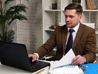 Naklejka premium A businessman checks data from a report in a laptop. Accountant at work.