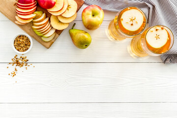 Glasses of beer with apple and peer on white wooden table top view copy space