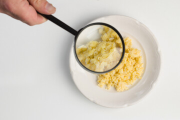 Millet porridge on a white plate under a magnifying glass. Vegetarian healthy food