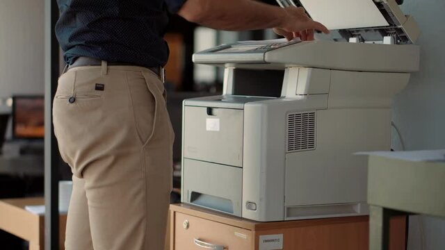 Man Finger Press Buttons On Multifunctional Copier.Man Using Printer Or Scanner In Office.Businessman Printing Document On Workplace.Businessman Working In Office And Preparing Documents For Signature