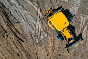 new yellow construction bulldozer at a construction site during work shot by drone