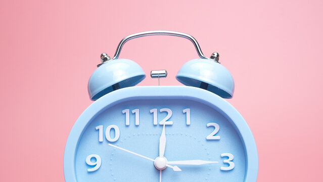 Blue alarm clock time 12.15 am or pm, on pink background, Copy space for your text, Time concept. .