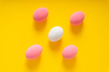 Top view of White and pink eggs over yellow background.