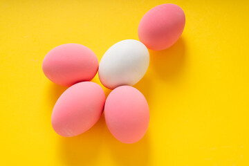 Top view of White and pink eggs over yellow background.