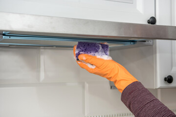 male hands in protective gloves cleaning the kitchen hood with rag and spray bottle