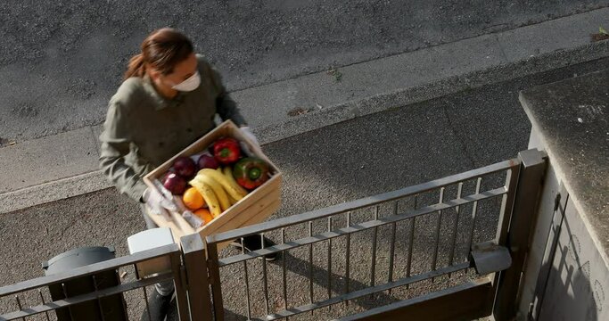 MS HA Woman wearing protective mask and gloves delivering fresh vegetable and fruit to senior woman / Florence, Tuscany, Italy