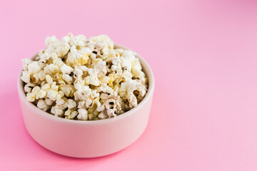 Popcorn in a pink bowl on pink background close-up