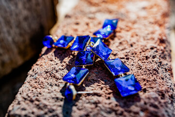 Costume jewelry for a festive day, long earrings with large square blue stones and an ultramarine bracelet. Elegant accessories on a dry wooden surface on natural elements