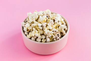 Popcorn in a pink bowl on pink background
