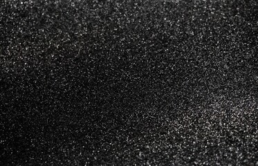 Black glitter texture. Glitz scattering surface. Dark festive background.