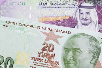 A close up image of a red, yellow and green twenty Turkish lira bank note with a five Saudi riyal...