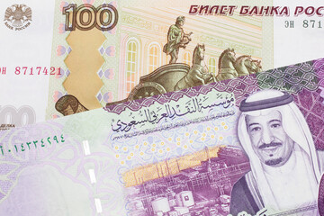 A close up image of a one hundred Russian ruble bank note close up with a five Saudi riyal bank note