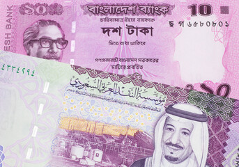 A red ten taka note from Bangladesh, close up in macro with a five Saudi riyal note