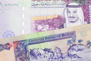 A colorful two dollar bill from Belize in close up macro with a colorful five riyal, Saudi Arabian bank note