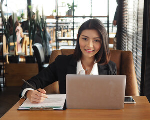 
Business woman hand writing on application form with a pencil in the office.Woman in suit sitting with notebook computer.