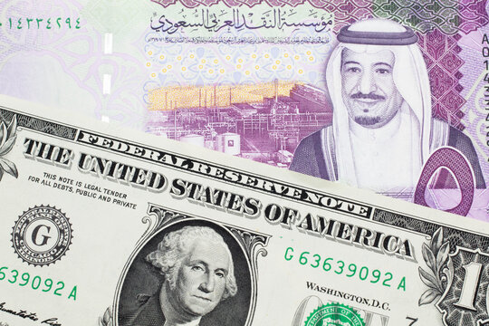 A close up image of a one American dollar note close up in macro with blue and green five Saudi riyal bank note from Saudi Arabia and the Saudi Arabia