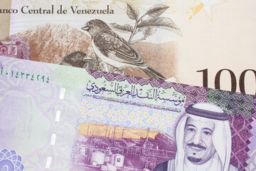 A one hundred Bolivar note from Venezuela with a five riyal note from Saudi Arabia close up in macro