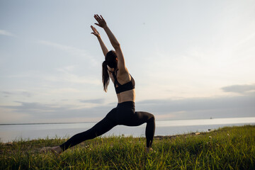 Fototapeta na wymiar young athletic girl is engaged in yoga warrior pose outdoor