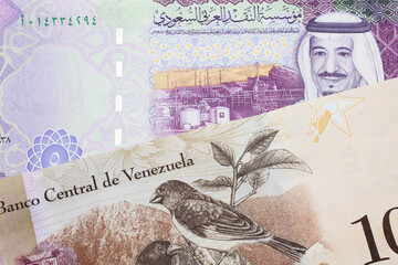 A one hundred Bolivar note from Venezuela with a five riyal note from Saudi Arabia close up in macro