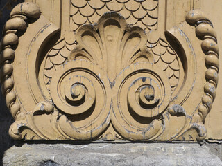 two spirals: ornament carved in ochre painted wood on a facade