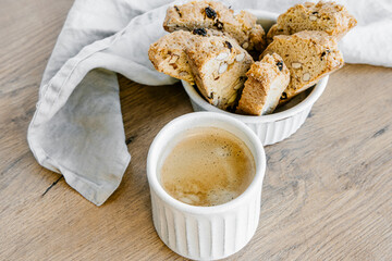 Freshly baked almond biscottis with cup of cappuccino on wooden background. Breakfast food concept. 