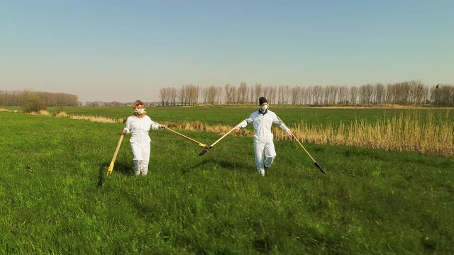 WS People wearing protective suits walking in distance in field / Prinsenbeek, Noord-Brabant, Netherlands
