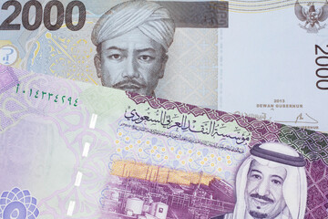 A gray two thousand Indonesian rupiah bank note with a five Saudi riyal note 