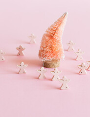 Coconut fiber orange Christmas tree and wooden angels on pink background, zero waste festive concept.