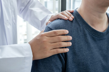 physiotherapists provide physical assistance to male patients with shoulder injuries massage their shoulders for muscle recovery in the rehabilitation center.