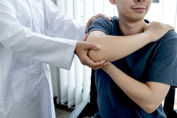 Obraz premium Female physiotherapists provide assistance to male patients with elbow injuries examine patients in rehabilitation centers. Physiotherapy concepts