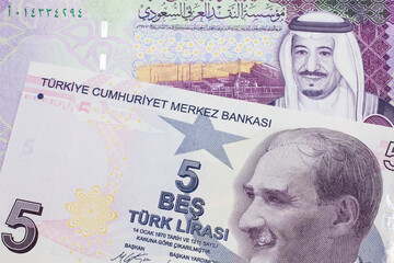 A close up image of a purple five Turkish lira bank note with a five Saudi riyal bill in macro from Saudi Arabia
