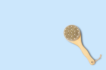 Dry massage brush on a blue background. Natural bristles. Copy space, flat lay