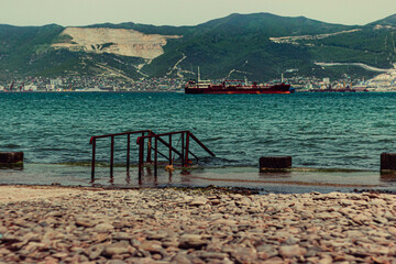Metal railings for the disabled descent into the water on the sea beach. Mountain and sea view on black sea coastline. 